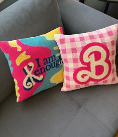 two decorative pillows sitting on top of a gray couch in front of a blue sofa