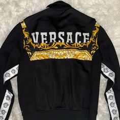 New -Versace Barocco Logo Jacket Stand Collar Ribbed Cuffs And Hem Side Tapes With Medusa Pattern Barocco Motif Rear Logo Print Zip Closure Side Pockets Color: Black / Gold 83% Viscose, 17% Elastane Made In Italy See More Jackets And Clothing Material: 83% Viscose, 17% Elastane See More Jackets And Clothing Designer Fall Outerwear With Logo Print, Designer Logo Print Outerwear For Fall, Luxury Long Sleeve Outerwear With Monogram Print, Designer Monogram Print Long Sleeve Outerwear, Designer Long Sleeve Outerwear With Monogram Print, Designer Long Sleeve Track Jacket For Fall, Versace Man, Versace Jacket, Clothing Material