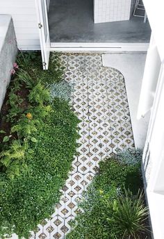 a white door and some plants on the side of a building with a tiled floor