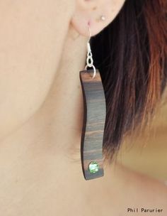 a close up of a person wearing some kind of wooden earring with green stones