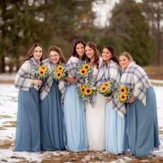 a group of women standing next to each other in the snow with sunflowers