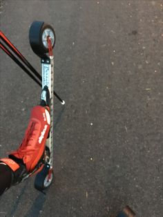 a person riding a scooter with two wheels on the street next to a pole