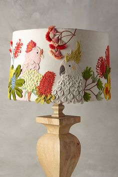 a lamp that is on top of a wooden base with flowers and birds painted on it