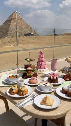 a table with desserts on it in front of the pyramids