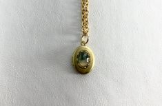 This sweet, small, OVAL antique brass locket has a faceted Moss Agate cabochon set on the front.  The cabochon sits in a brass lace edged setting. It hangs on a 16" gold-plated stainless-steel chain necklace.  The locket is approximately 11x16mm.  The cabochon is 5x7mm.  Arrives in an eco-friendly jewelry box, ready for gifting. MORE lockets in my shop! FREE SHIPPING! THANK YOU FOR VISITING MY SHOP! Oval Cabochon Brass Necklace, Brass Cabochon Oval Pendant Jewelry, Brass Oval Pendant With Cabochon, Gold Oval Pendant Locket Necklace, Nickel Free, Oval Cabochon Pendant In Brass, Handmade Brass Gold Locket Necklace, Handmade Gold Brass Locket Necklace, Adjustable Gold Cabochon Necklace, Handmade Oval Brass Locket Necklace