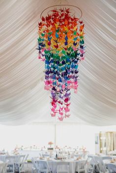 a chandelier hanging from the ceiling in a tent with tables and chairs under it