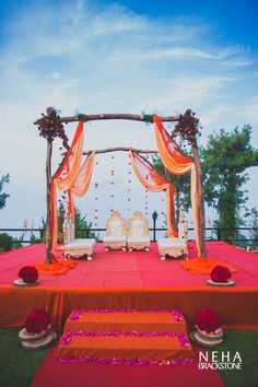 an outdoor wedding setup with orange and red draping