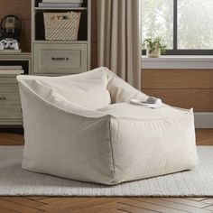 a white bean bag chair sitting on top of a rug in front of a window