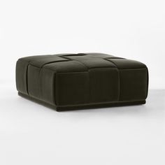 an ottoman that is made out of black leather and has four squares on the top