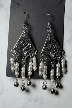 Ethereal drama for any special occasion. Wedding, Anniversary, Prom, Graduation, Quinceañera & Sweet 16 Beautiful filigree dangle earrings, with pearl and silver glass beads, clear seed beads with small silver bell accents. Hypoallergenic, stainless steel earring hooks. Lead and nickel free Zinc alloy findings. Soft Silicone Earring backs. *The following items cannot be returned - Earrings (this is for hygiene reasons) #Ethereal #EastTericiaTradingCo #UniqueGift #ChandelierEarrings #GiftForHer # Winter Solstice Gifts, Yule Gifts, Yule Gift, Silver Bells, Earrings Beaded, Earrings Unique, Winter Solstice, Gifts Christmas, Gifts Unique