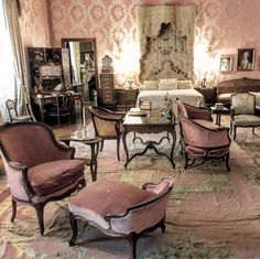 a living room filled with lots of furniture and walls covered in pink damasks