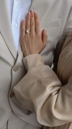 a woman wearing a white suit and holding her hands together