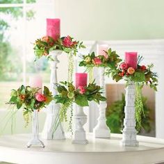 three white vases with pink and green flowers in them sitting on top of a table