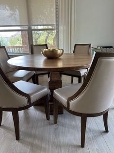 a wooden table with chairs around it and a bowl on top of the dining room table