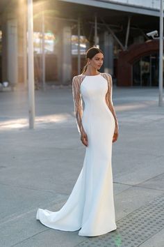 a woman in a white dress standing on the sidewalk