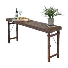 a wooden table topped with a potted plant next to a bottle of wine