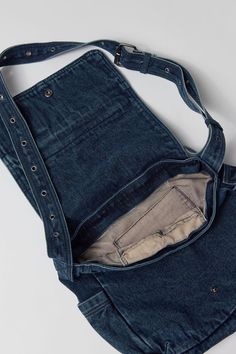 an old pair of blue jeans is in the pocket of a bag on a white surface