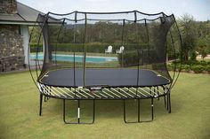 a trampoline is in the grass near a pool