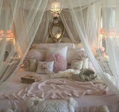 a canopy bed with pink and white pillows