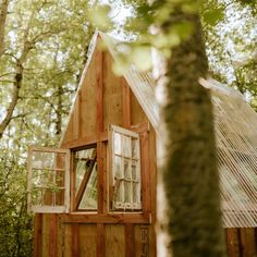 a small wooden house in the woods with windows and a roof made out of wood