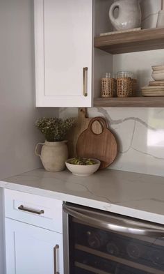 a kitchen with white cupboards and an oven in the corner, filled with dishes