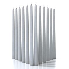 several white candles lined up in a row on a white surface with shadows coming from them