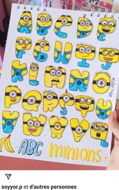 a person holding up a sticker with the letters and minions on it in front of them