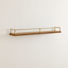 a wooden shelf with metal bars on the top and bottom, against a white wall