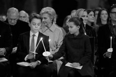 people holding candles in front of them at a ceremony with other people standing behind them