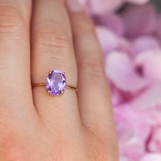 a woman's hand holding a ring with an amethorate stone on it