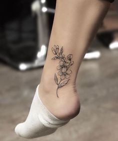 a woman's foot with a small flower tattoo on the left side of her leg