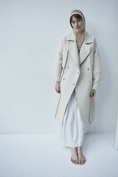 This sweeping statement coat exudes oversized elegance with its wide lapels leading to a romantic deep V neckline. Falling just above the ankles, the Snegurochka Cream Wool Hemp Shell Buttons Coat is both cozy and sophisticated. Made from a blend of durable hemp and wool fibers, its sturdy structure is punctuated with uniquely handcrafted ceramic shell buttons. Lined.Composition 40% Hemp 60% Wool and it´s undyed.Lining 100% viscoseTrimming 100% ceramic glazed handmade shell buttonsSizesOversize. Oversized Long Outerwear In Winter White, Oversized Cream Wool Coat For Fall, Oversized Double-breasted Wool Coat For Spring, Oversized Double-breasted Spring Wool Coat, Winter White Long Outerwear For Spring, Oversized Beige Wool Coat For Spring, Oversized Long Wool Coat For Spring, Oversized Chic Wool Coat For Fall, Oversized Beige Shawl Collar Outerwear