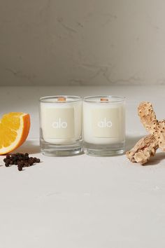 two candles sitting next to an orange slice on a white counter top with other items surrounding them