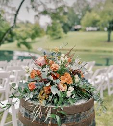 a wooden barrel with flowers and greenery on it for an outdoor wedding ceremony in the park