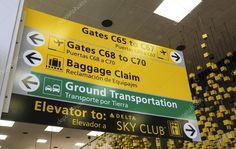 an airport sign hanging from the ceiling in front of a building with yellow and black signs