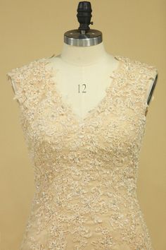 a dress on a mannequin in front of a beige background with white flowers