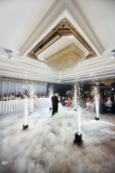 a bride and groom dance in the middle of a cloud filled floor at their wedding reception