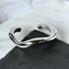 This unique bangle bracelet is designed to make waves and add a bold touch to any outfit. Size: One Size Material: Stainless Steel Plating: Silver Bracelet is 100% nickel-free and cadmium-free Bracelet is hypoallergenic and tarnish resistant Trendy Silver Bangle Bracelet, Everyday Modern Metal Bangle, Modern Twist Polished Bangle Cuff Bracelet, Modern Sterling Silver Bangle Bracelet, Silver Tarnish Resistant Minimalist Bangle, Silver Minimalist Tarnish-resistant Bangle, Modern Tarnish-resistant Cuff Bracelet Bangle, Minimalist Silver Tarnish-resistant Bangle, Modern Tarnish-resistant Bangle Cuff Bracelet