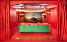 a living room with red curtains and a green couch