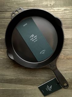 an empty pan with a business card on the side sitting on a wooden table next to it