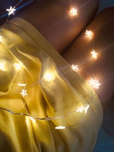 a woman laying on top of a bed under a blanket covered in white star lights