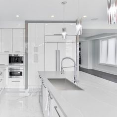 a large kitchen with white cabinets and marble counter tops