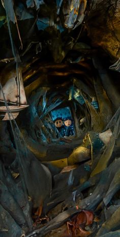 the inside of a cave filled with lots of rocks and debris, looking up at two people