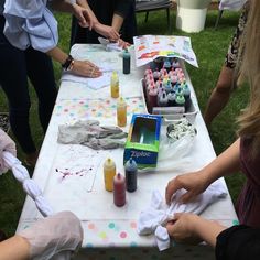 several people are painting at a table with craft supplies on it and one person is wearing white gloves