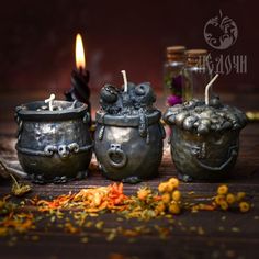 three metal pots with candles in them on a table