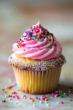 a cupcake with pink frosting and sprinkles on it's top