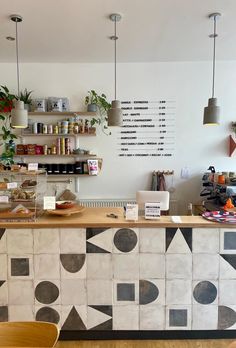 the counter in this coffee shop is decorated with black and white geometric tiles, along with potted plants