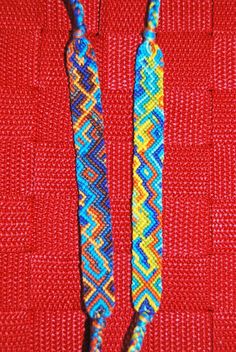 two beads are sitting on a red surface with blue and yellow bead designs in the middle