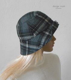 a woman wearing a plaid hat with long blonde hair in front of a white wall