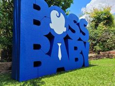 a blue sign that says boss baby on it's side in front of some trees